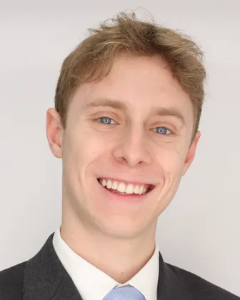 Ben Jordan, smiling, in a gray suit and a light blue tie